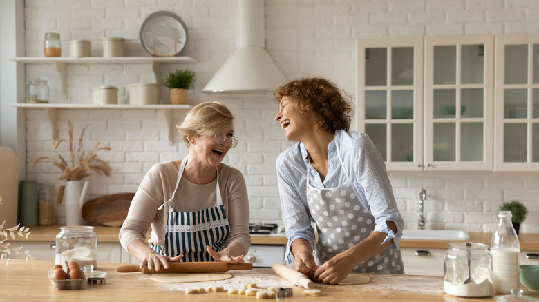 two women rolling dough and laughing