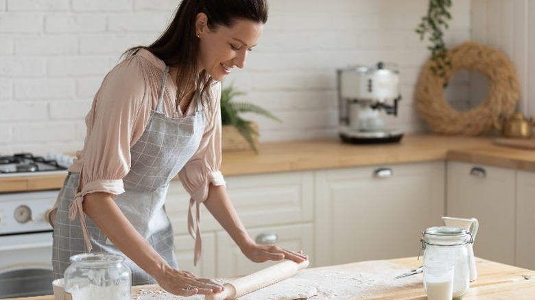 woman rolls out dough on counter