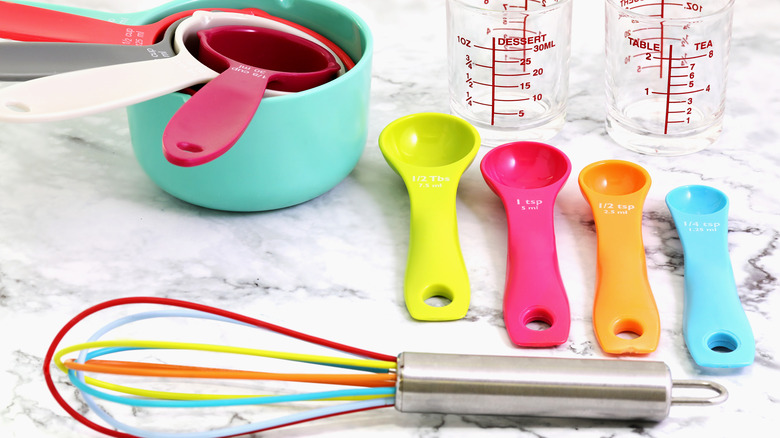 Measuring cups and spoons with a colorful whisk