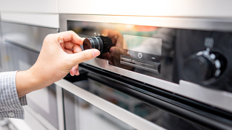 Hand turning a dial on an oven