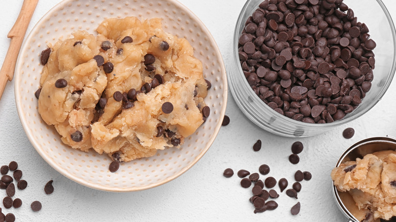 A bowl of chocolate chip cookie dough with extra chocolate chips on the side