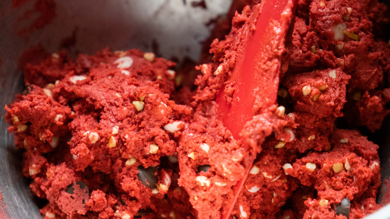 a red spatula in a bowl of red velvet cookie dough