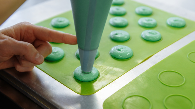 piping macarons on a baking mat