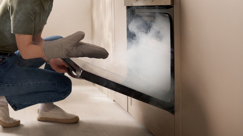 Woman opening smoking oven