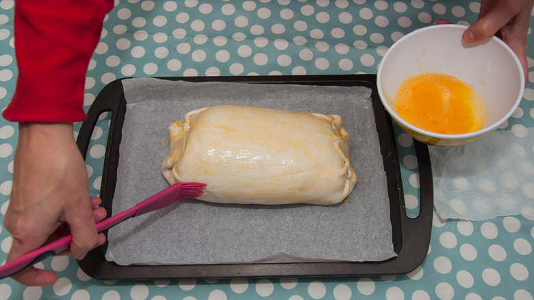 Brushing beef Wellington with egg