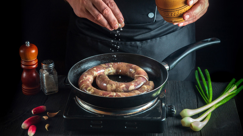 someone cooking sausage in a pan