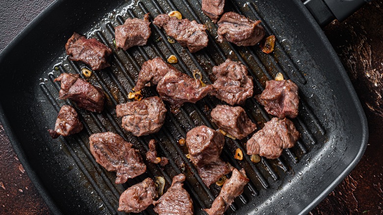 diced beef cooking on grill pan