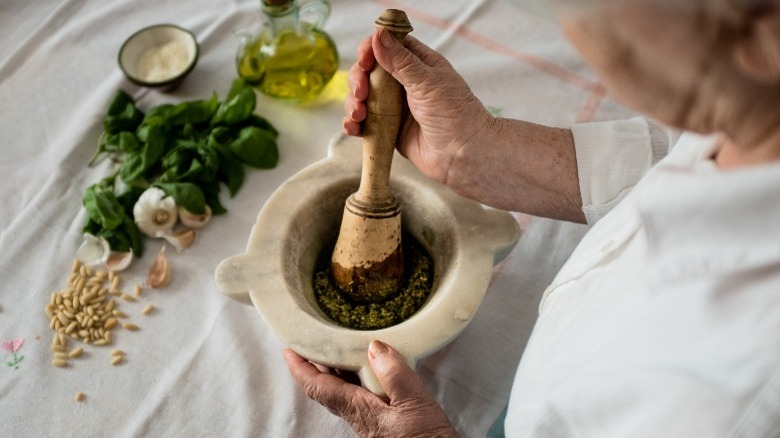 chef making pesto with mortar and pestle