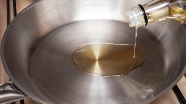 pouring oil into stainless steel pan