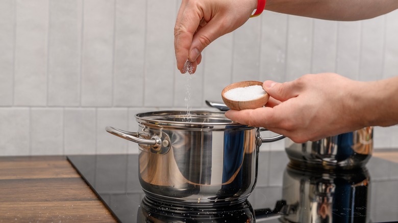 person adding salt to pot of water