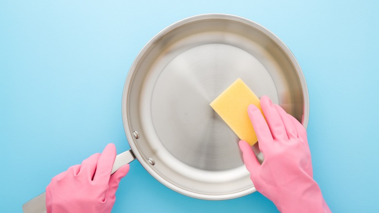 hands cleaning stainless steel pan