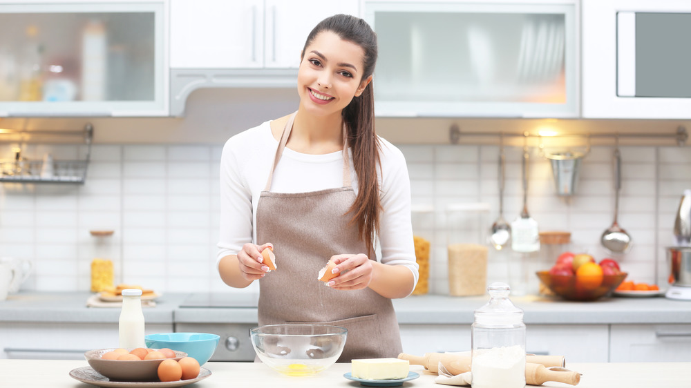 woman cracking eggs in kitchen