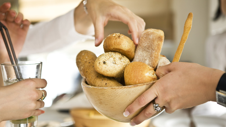 Hand reaching in to take roll from bread basket