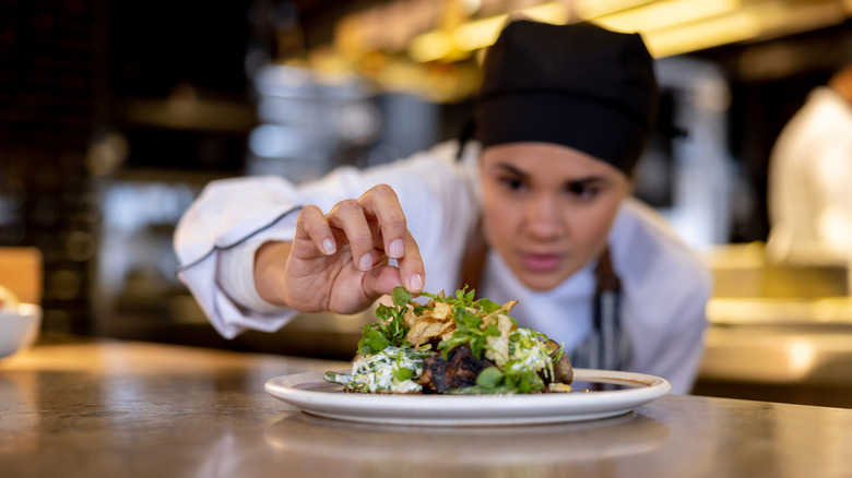 Chef finishing plate in kitchen