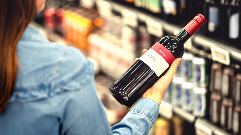 woman holding red wine bottle