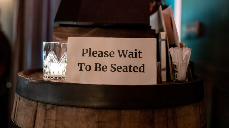 "Please wait to be seated" sign