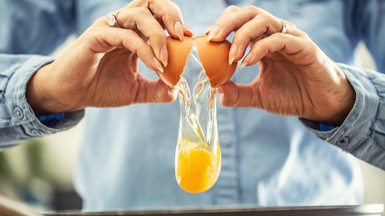 man cracking an egg into pan