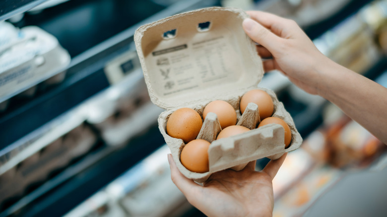 person holding egg carton at grocery store