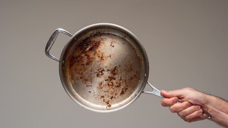 person holding sticky dirty pan