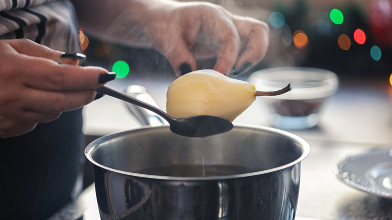 Peeled pear in ladle above pan on stove