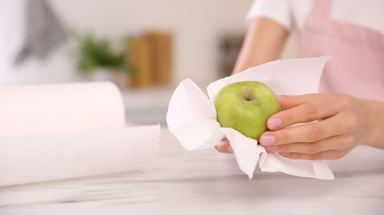 Woman drying apple with paper towel