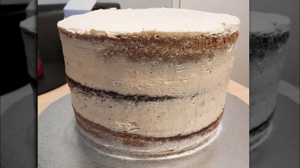 Crumb coat frosting on a vanilla and chocolate-layered cake