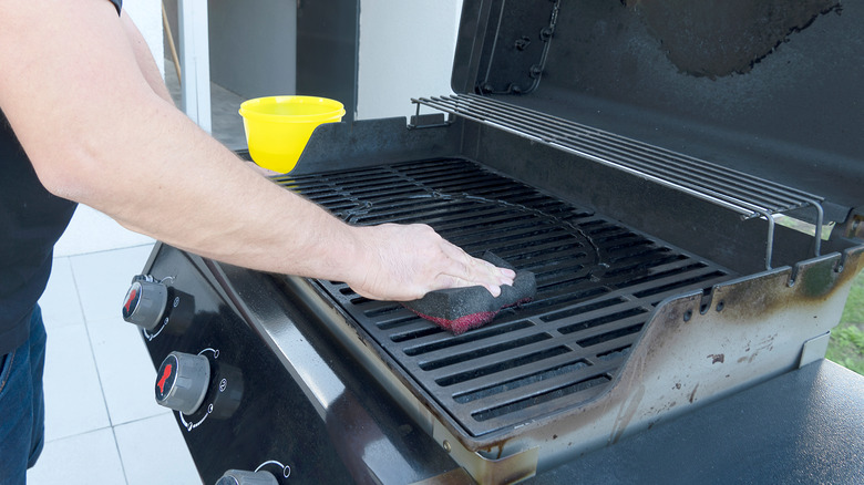 man cleaning grill 