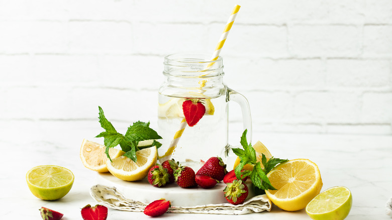 Cut strawberries and lemons next to glass mug