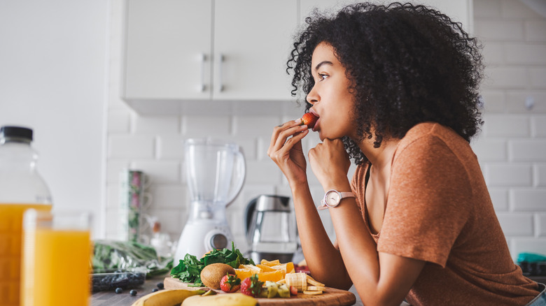 Woman eating fruit at counter