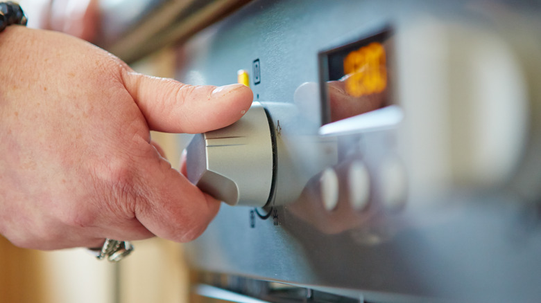 Hand adjusting oven setting