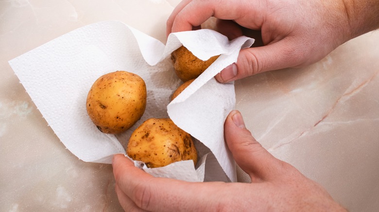 Person drying potatoes with paper towel