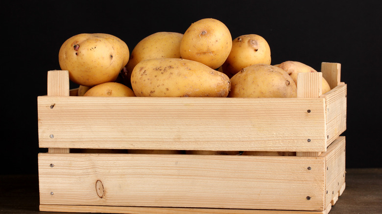 Ripe potatoes in wooden box