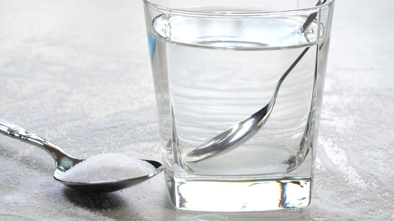 Salt water in a glass cup and salt in a teaspoon