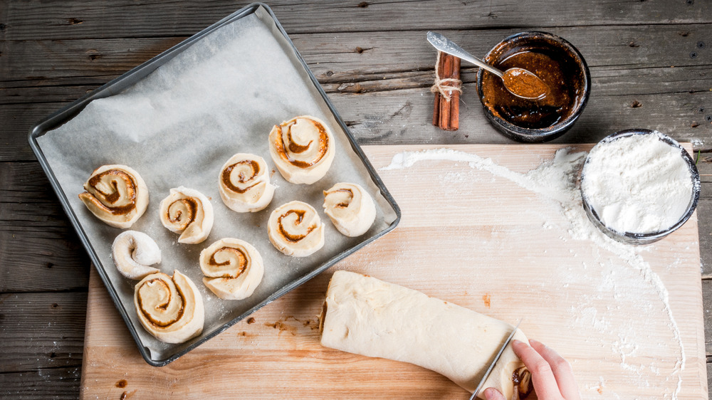 cutting up tray of cinnamon rolls