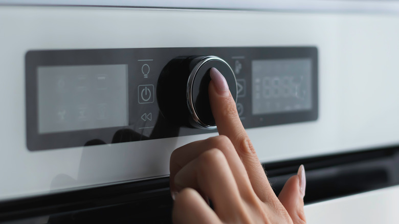 Finger touching button on oven