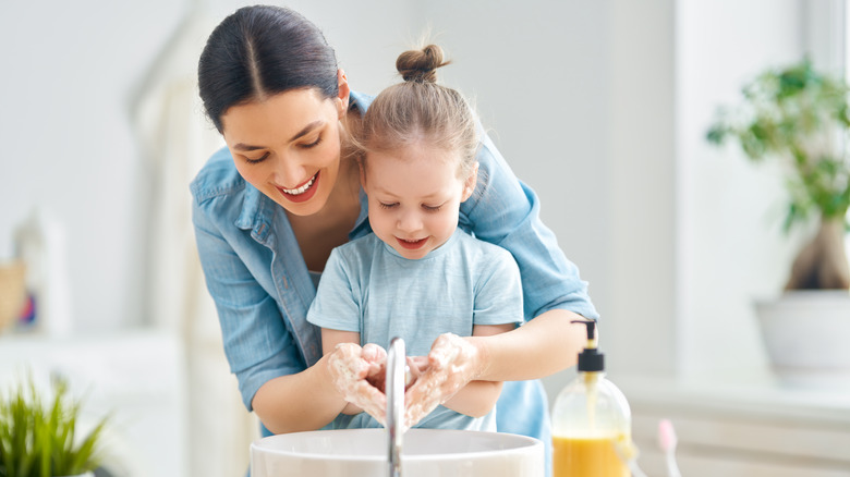 mother and daughter wash hands