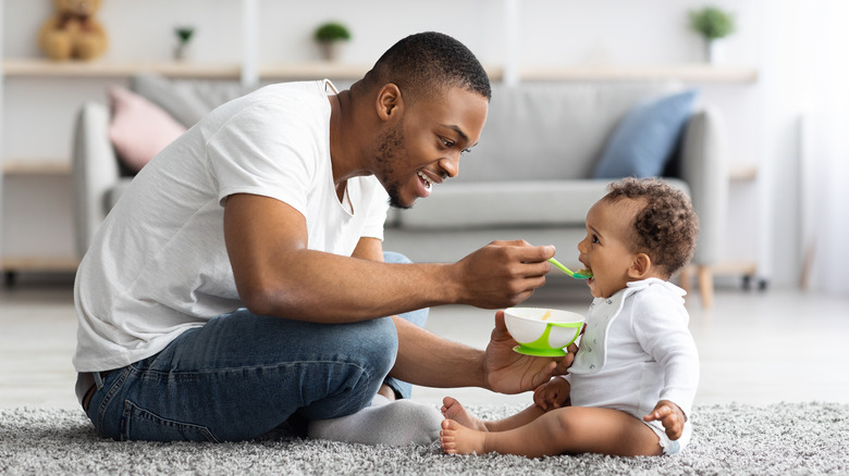 father feeding baby on floor