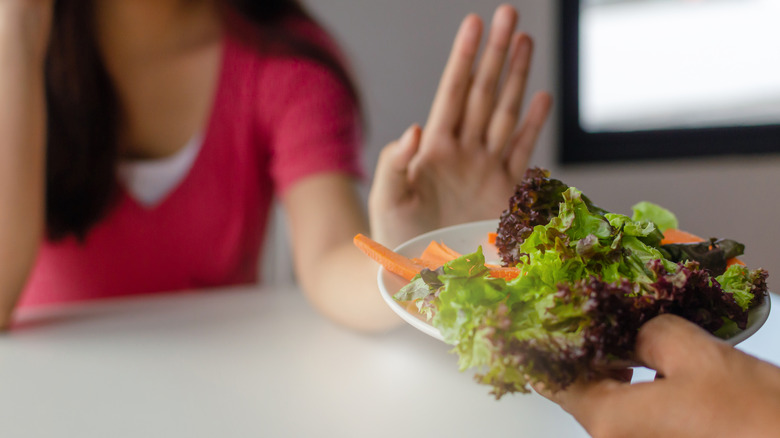 woman's hand up against salad