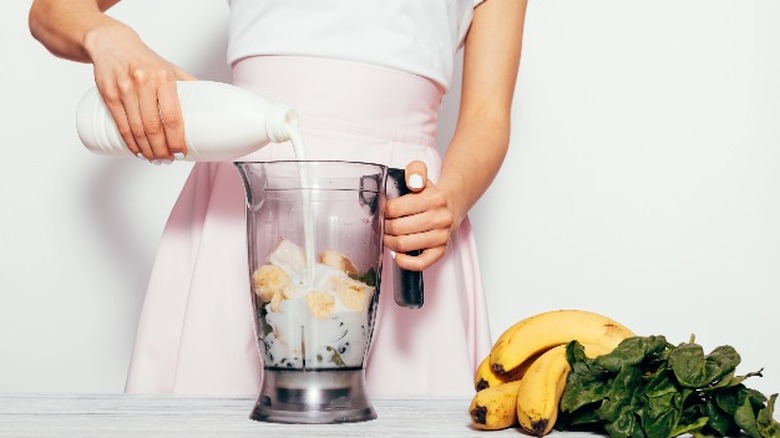 adding milk to a smoothie