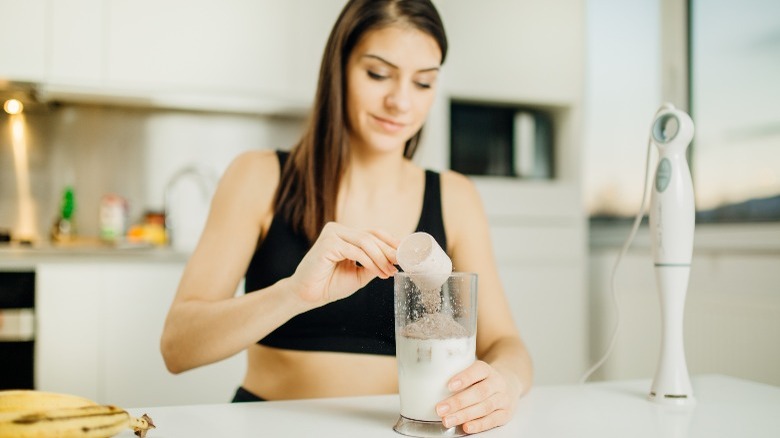 woman adding protein to smoothie