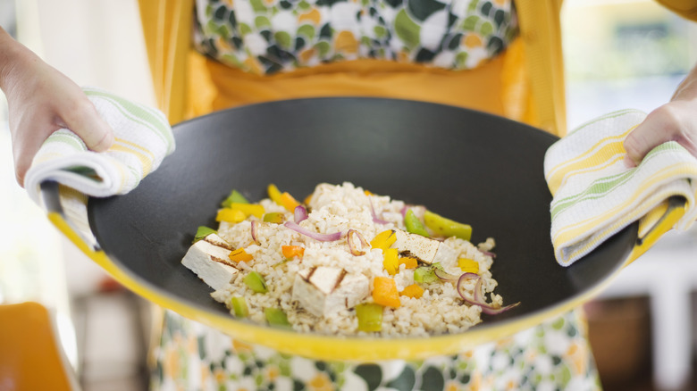 Stir-fry in a wok being carried to the table