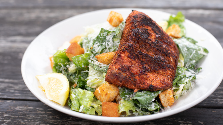 blackened salmon with caesar salad in white bowl