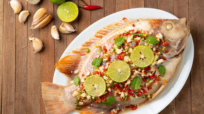 cooked fish on white plate with garlic and lime