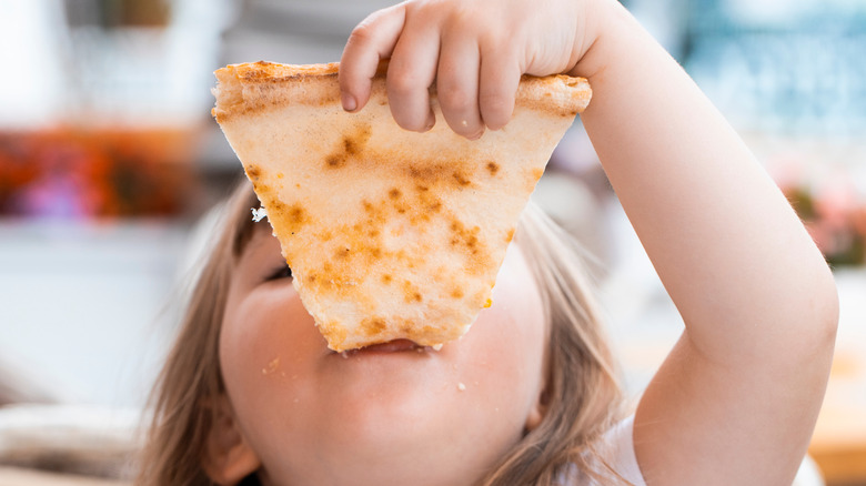 child eating a large piece of pizza