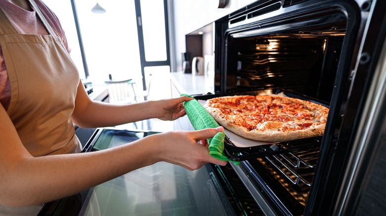 woman taking pizza out of the oven