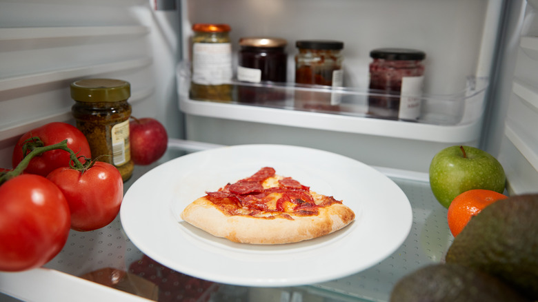 leftover pizza on a plate in the fridge