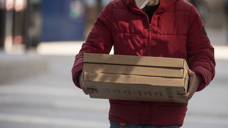 man carrying three boxes of pizza