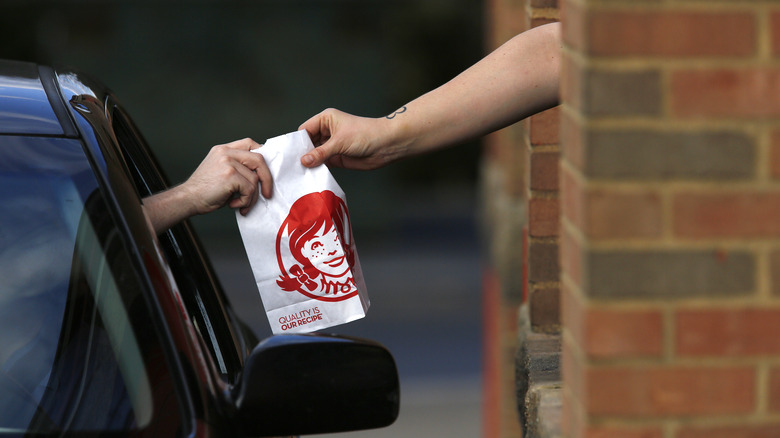 Customer getting Wendy's order at drive-thru window