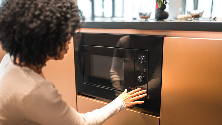 woman turning on the microwave