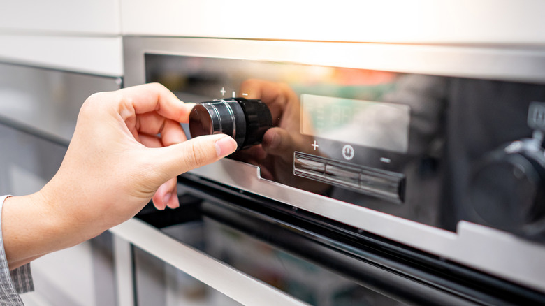 person setting the temperature on an oven